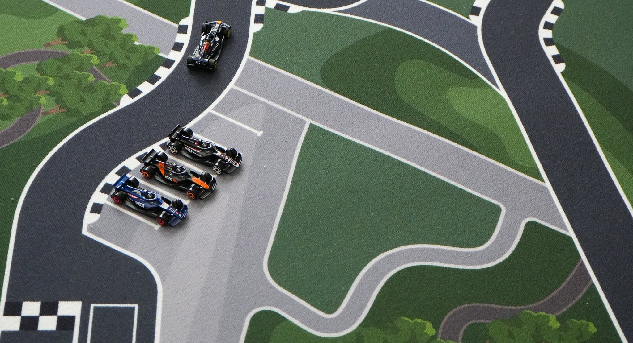 Model F1 race cars on a race track with greenery and a lake